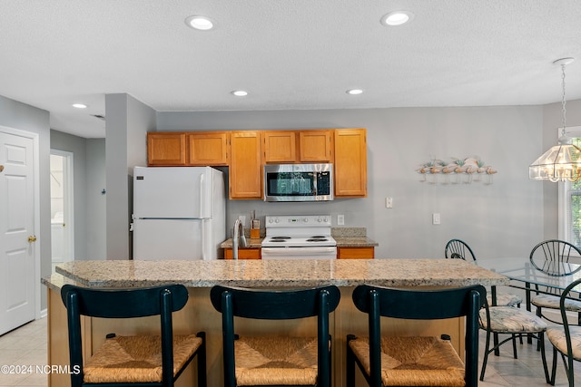 kitchen featuring white appliances, a kitchen breakfast bar, a kitchen island, and light tile floors