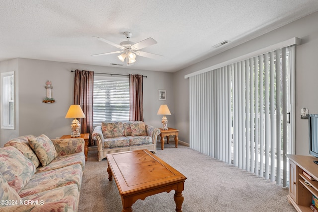 living room with a healthy amount of sunlight, a textured ceiling, carpet, and ceiling fan