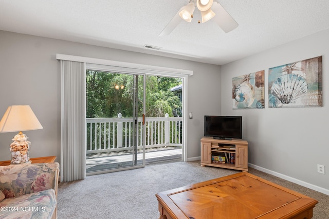 carpeted living room featuring ceiling fan and a textured ceiling