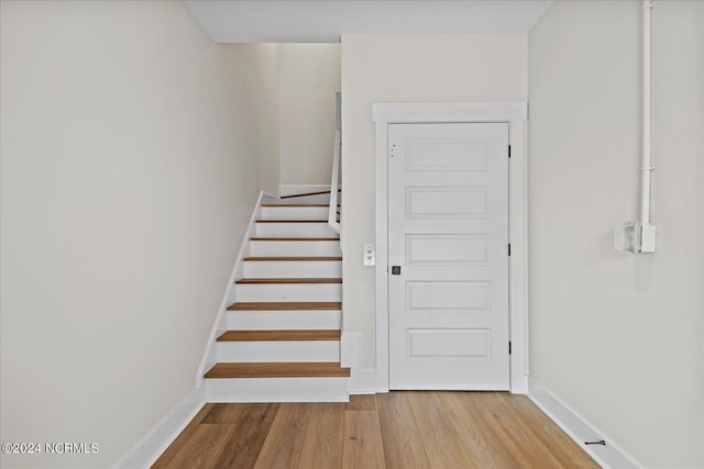 stairs with wood finished floors and baseboards