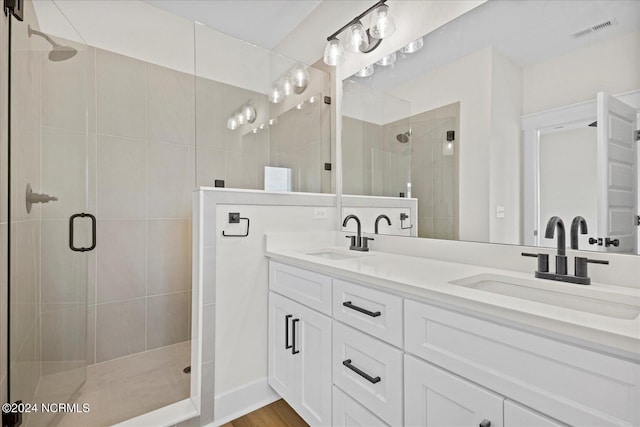 full bath featuring double vanity, a stall shower, visible vents, and a sink