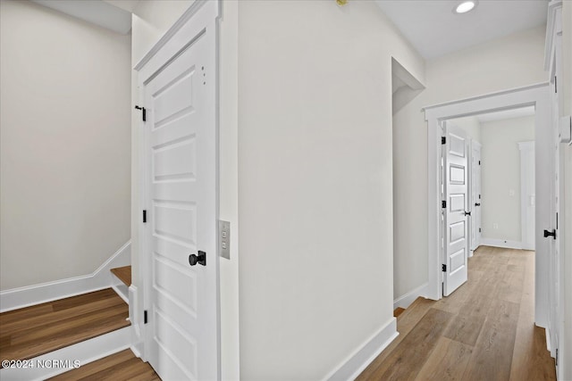 hall with light wood-type flooring, stairway, baseboards, and recessed lighting