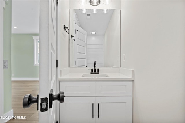 bathroom with visible vents, vanity, baseboards, and wood finished floors