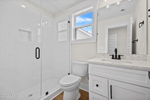 full bathroom with visible vents, toilet, a stall shower, vanity, and wood finished floors