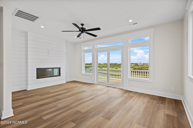 unfurnished living room featuring light wood-type flooring, a large fireplace, baseboards, and visible vents