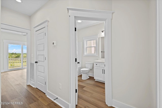 hallway featuring light wood-type flooring, baseboards, and a wealth of natural light