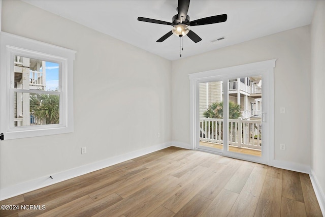 empty room featuring light wood finished floors, baseboards, visible vents, and a wealth of natural light