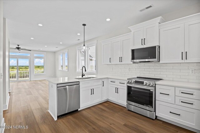 kitchen featuring stainless steel appliances, white cabinets, light countertops, and a sink