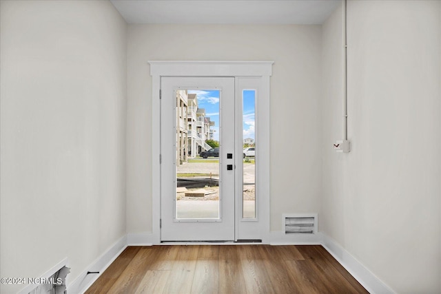 doorway with visible vents, baseboards, and wood finished floors