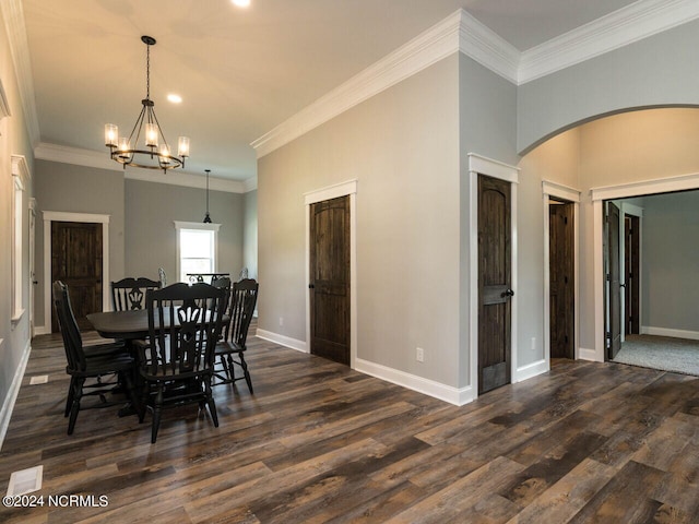 dining area featuring dark hardwood / wood-style flooring, crown molding, and an inviting chandelier