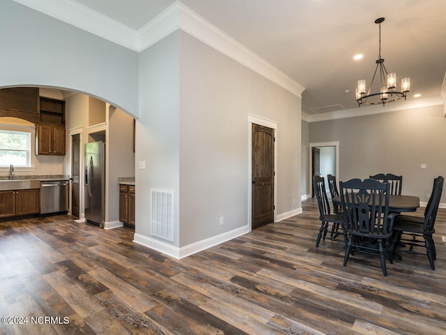 dining area with crown molding, dark hardwood / wood-style flooring, sink, and an inviting chandelier