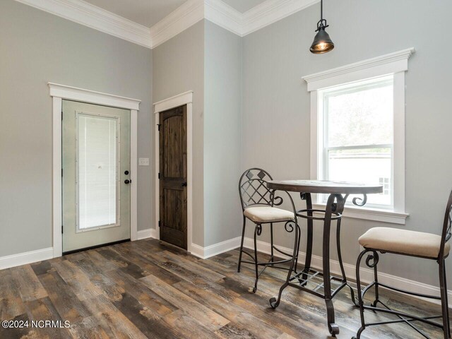 dining space featuring crown molding and dark wood-type flooring