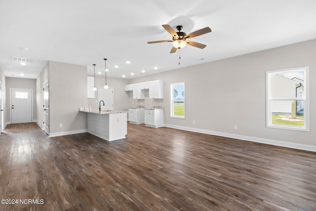 unfurnished living room featuring ceiling fan, sink, and dark hardwood / wood-style flooring