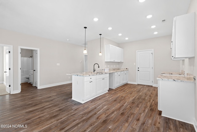 kitchen with dark hardwood / wood-style floors, white cabinetry, kitchen peninsula, hanging light fixtures, and light stone countertops