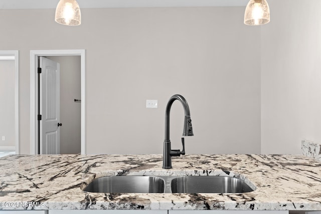 interior details with light stone countertops, decorative light fixtures, and sink