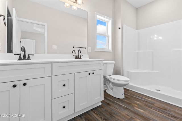 bathroom featuring hardwood / wood-style floors, walk in shower, vanity, and toilet