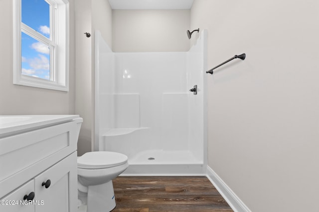 bathroom with hardwood / wood-style floors, walk in shower, vanity, and toilet