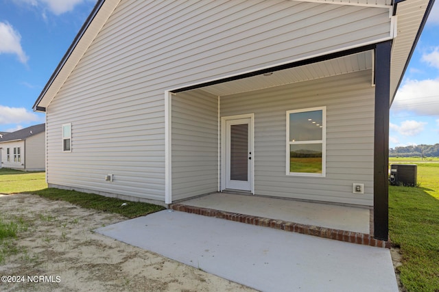 property entrance featuring a lawn, a patio area, and central air condition unit