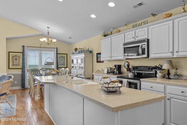 kitchen with an inviting chandelier, white cabinets, hanging light fixtures, appliances with stainless steel finishes, and light hardwood / wood-style floors