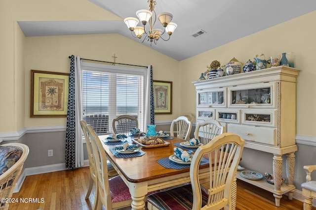 dining area with light hardwood / wood-style flooring, lofted ceiling, and a notable chandelier