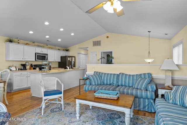 living room featuring ceiling fan, lofted ceiling, and light hardwood / wood-style flooring