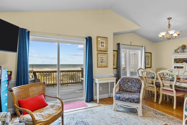 sitting room featuring light hardwood / wood-style flooring, a water view, vaulted ceiling, and an inviting chandelier