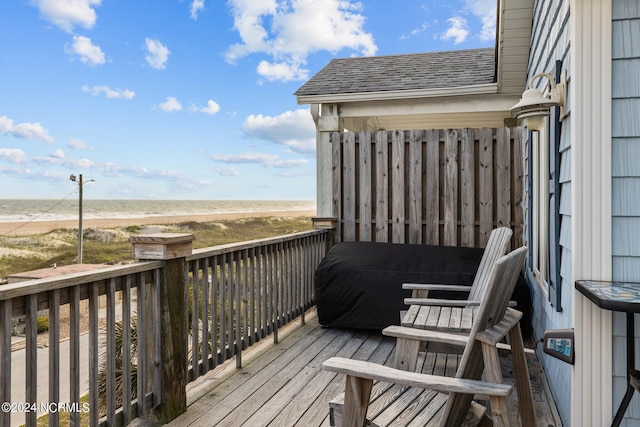 wooden deck featuring a water view and a beach view