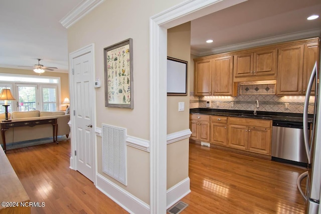 kitchen with sink, dishwasher, tasteful backsplash, ornamental molding, and light wood-type flooring