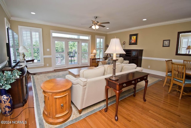 living room with crown molding, ceiling fan, and light wood-type flooring