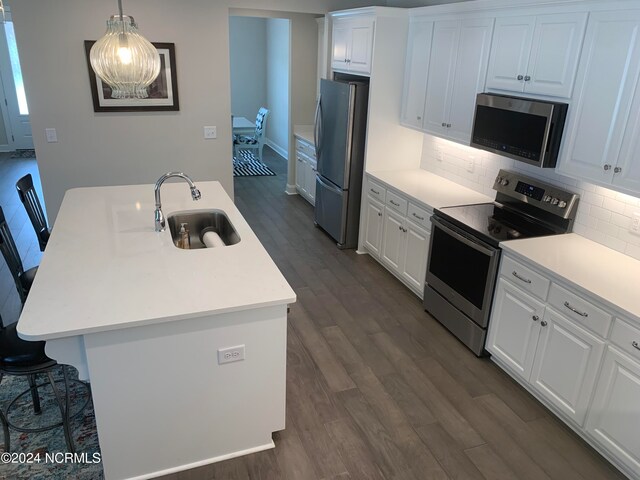 kitchen with dark hardwood / wood-style flooring, a center island with sink, appliances with stainless steel finishes, sink, and pendant lighting