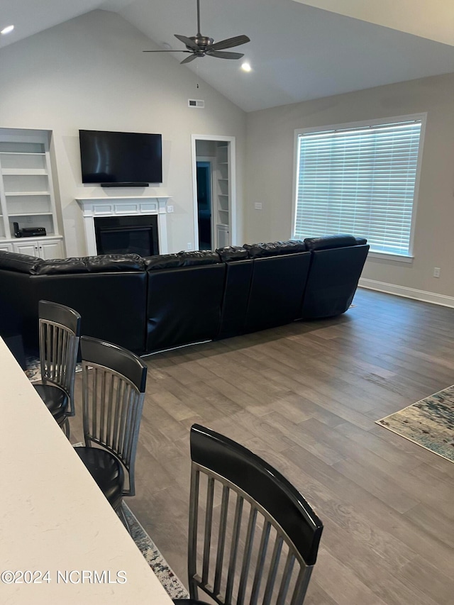 living room featuring built in features, ceiling fan, vaulted ceiling, and hardwood / wood-style flooring