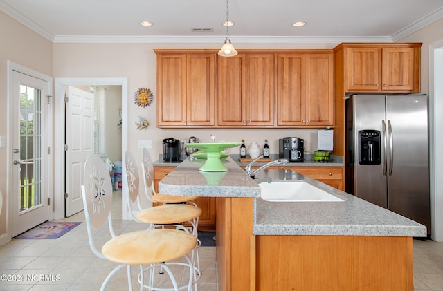 kitchen featuring a kitchen breakfast bar, stainless steel fridge, pendant lighting, sink, and light tile floors