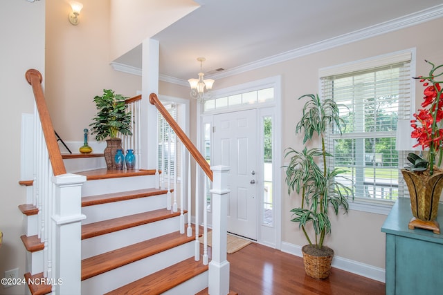 foyer entrance with crown molding, hardwood / wood-style flooring, and a notable chandelier