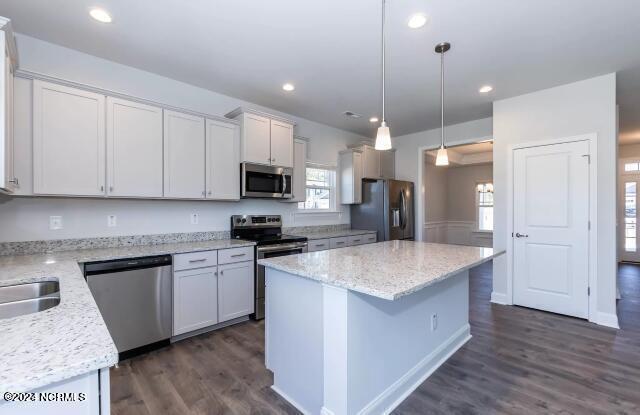 kitchen with white cabinetry, hanging light fixtures, stainless steel appliances, and light stone countertops