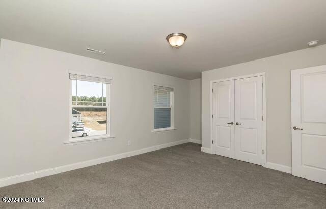 unfurnished bedroom featuring dark carpet and a closet