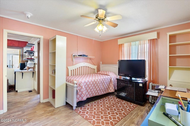 bedroom featuring a textured ceiling, ceiling fan, light wood-type flooring, and ornamental molding