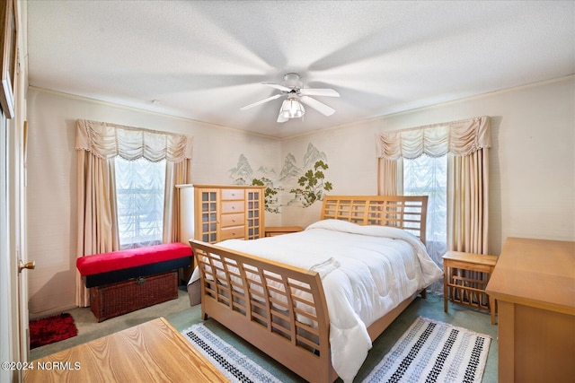 carpeted bedroom with a textured ceiling, multiple windows, and ceiling fan