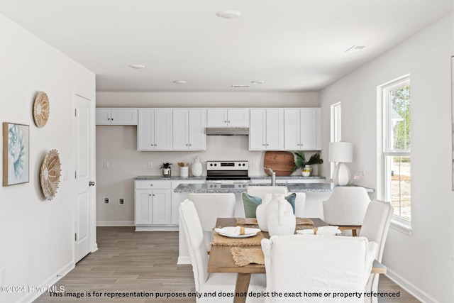 kitchen featuring light hardwood / wood-style floors, stainless steel electric range oven, white cabinets, and light stone counters