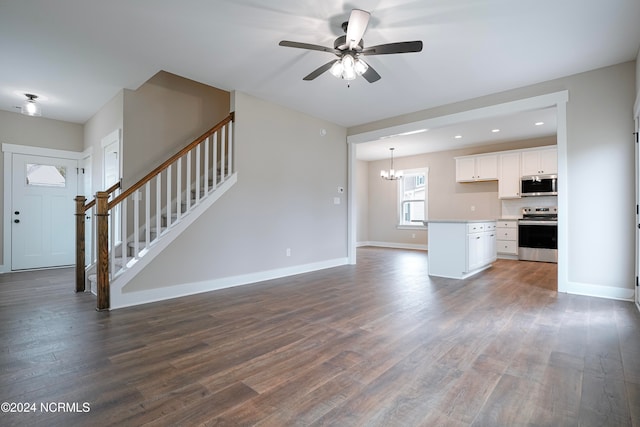 unfurnished living room featuring ceiling fan with notable chandelier and dark hardwood / wood-style flooring