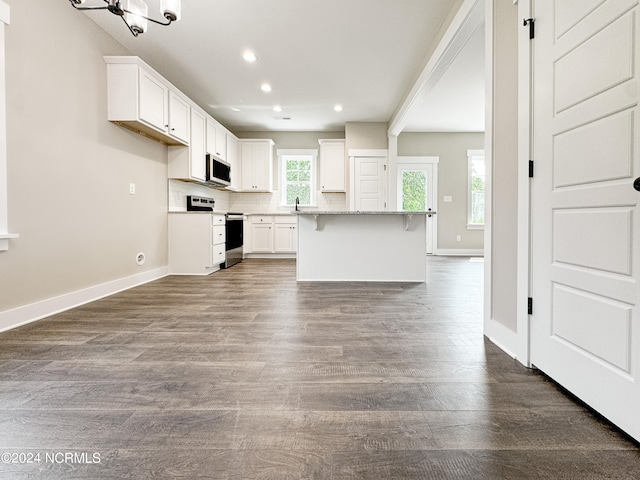 kitchen with light stone counters, white cabinetry, dark hardwood / wood-style floors, stainless steel appliances, and a center island