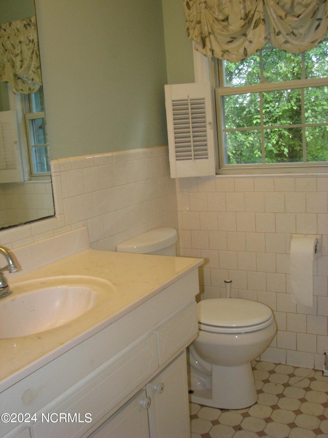 bathroom featuring tile patterned flooring, vanity, toilet, and tile walls