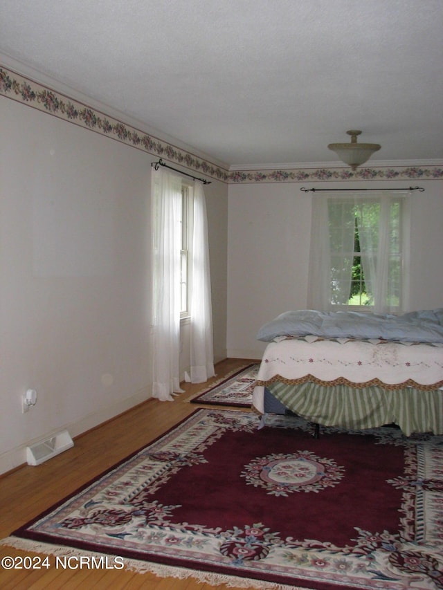 bedroom featuring wood-type flooring and ornamental molding