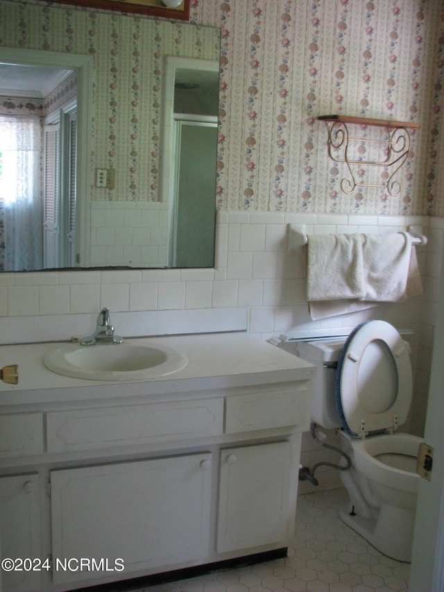 bathroom featuring tile patterned floors, walk in shower, vanity, and toilet