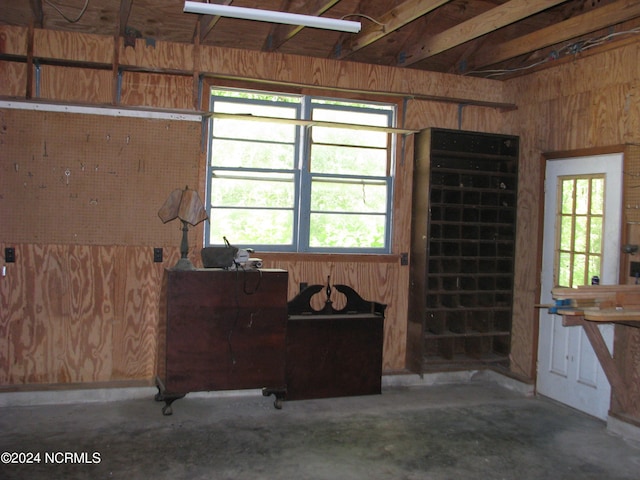 miscellaneous room with concrete flooring and wood walls