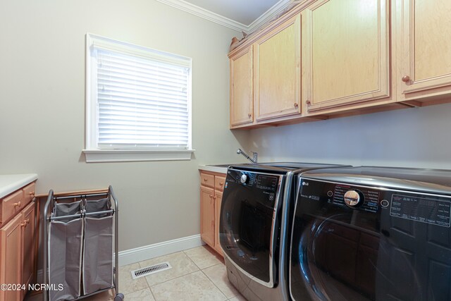 clothes washing area featuring washing machine and dryer, crown molding, light tile flooring, and cabinets