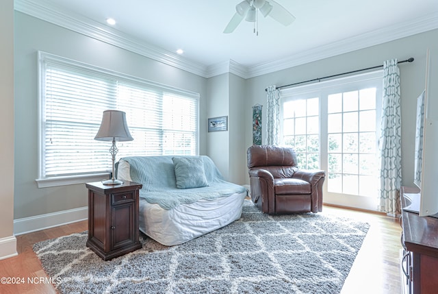 living room featuring ceiling fan, a healthy amount of sunlight, wood-type flooring, and ornamental molding