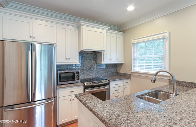 kitchen featuring white cabinets, stainless steel appliances, backsplash, ornamental molding, and sink