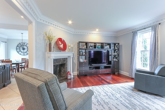 living room with crown molding, a fireplace, plenty of natural light, and light hardwood / wood-style flooring