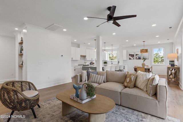 living room with ceiling fan, plenty of natural light, and light wood-type flooring