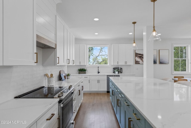 kitchen with decorative light fixtures, light stone countertops, white cabinetry, and appliances with stainless steel finishes